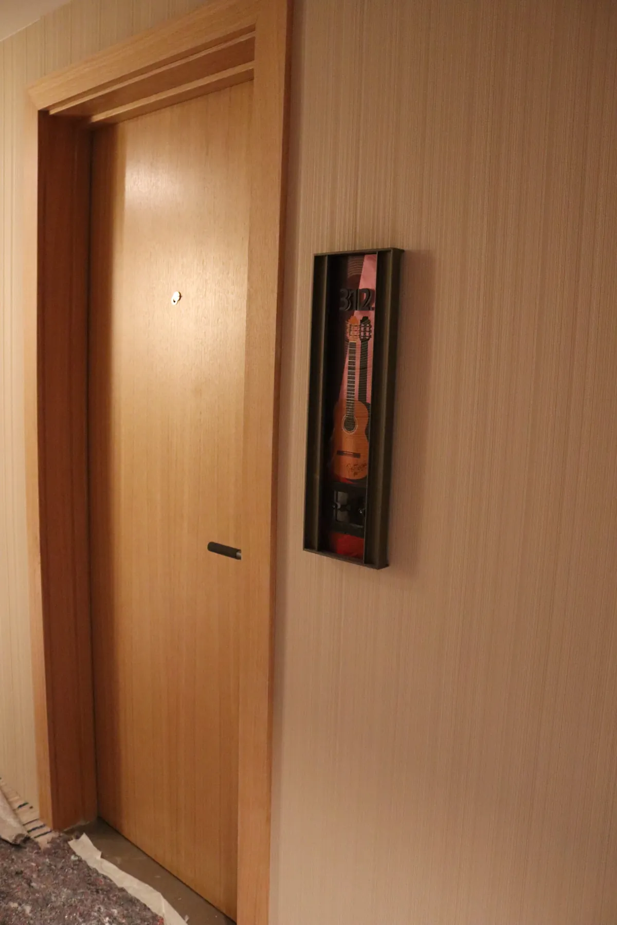 Puerta de habitación en madera junto a la vitrina de guitarra del Hard Rock