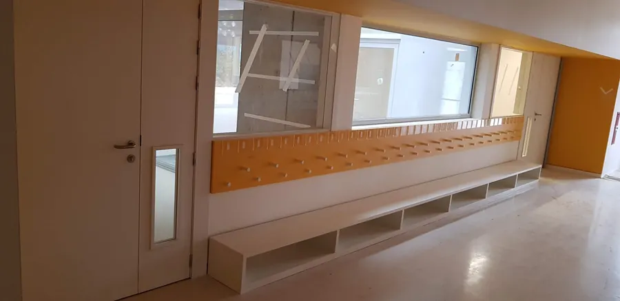 Corredor de colegio con bancada y perchero corrido de madera